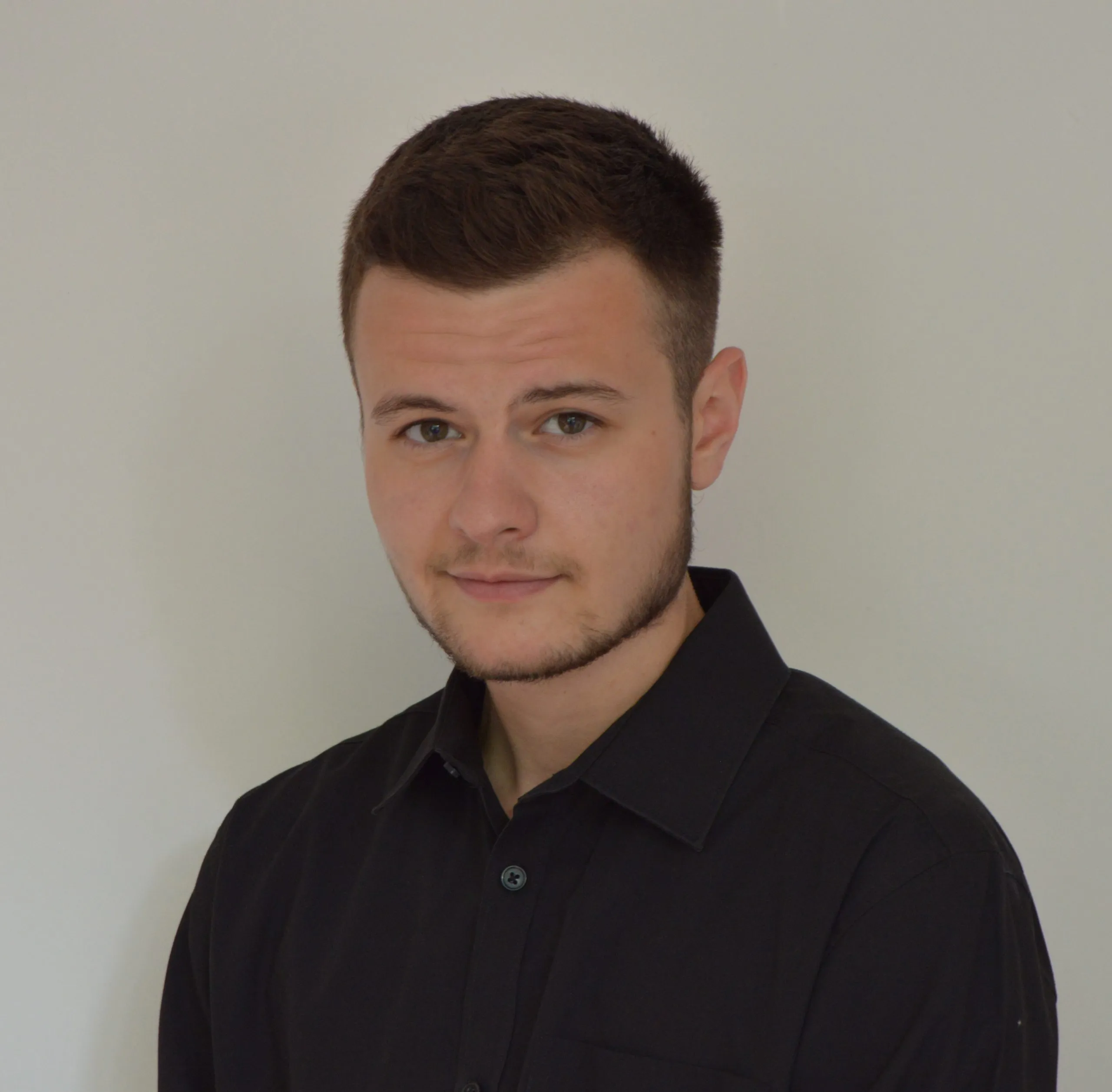 Headshot of Jacob wearing a black shirt in front of a white background.