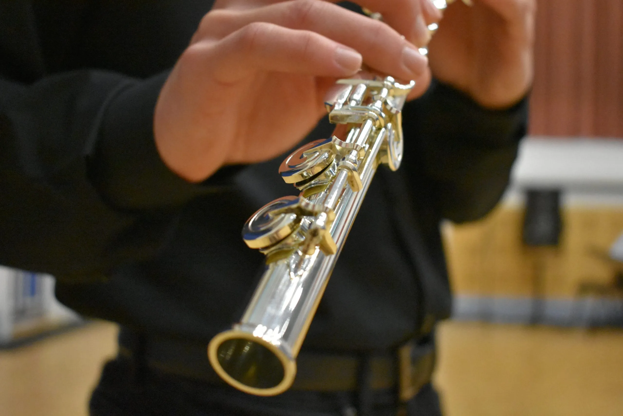 A closeup image of Jacob playing flute, showing the keys at the end of the flute with Jacob blurred in the background